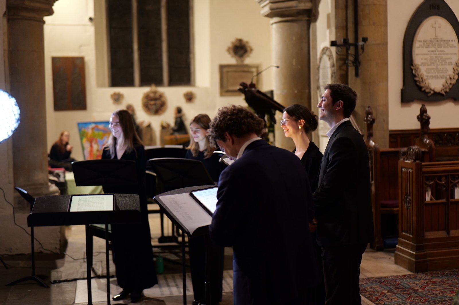 The singers performing by candlelight in a church